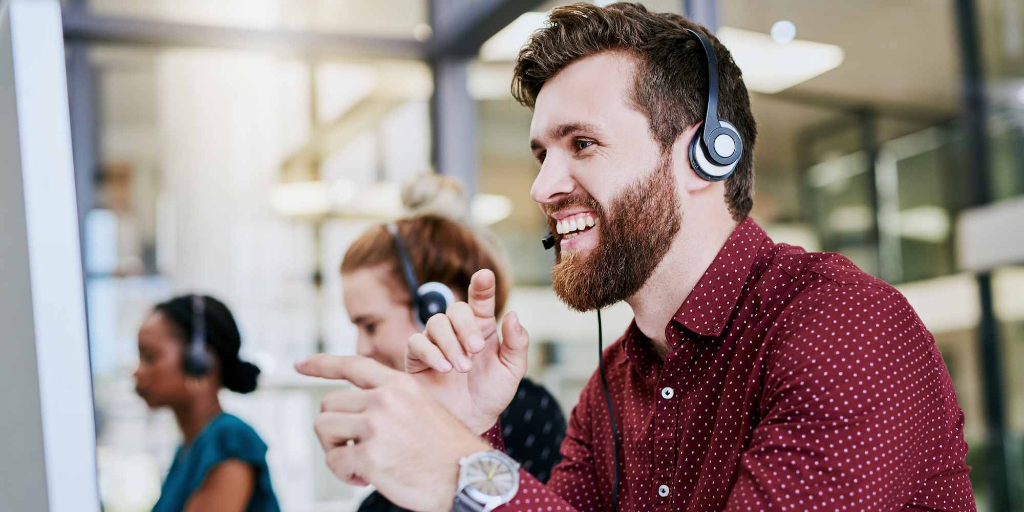 A man smiling and talking through his headphones.