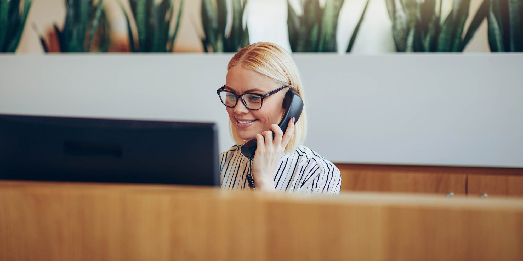 A woman talking on the phone and looking at her computer.